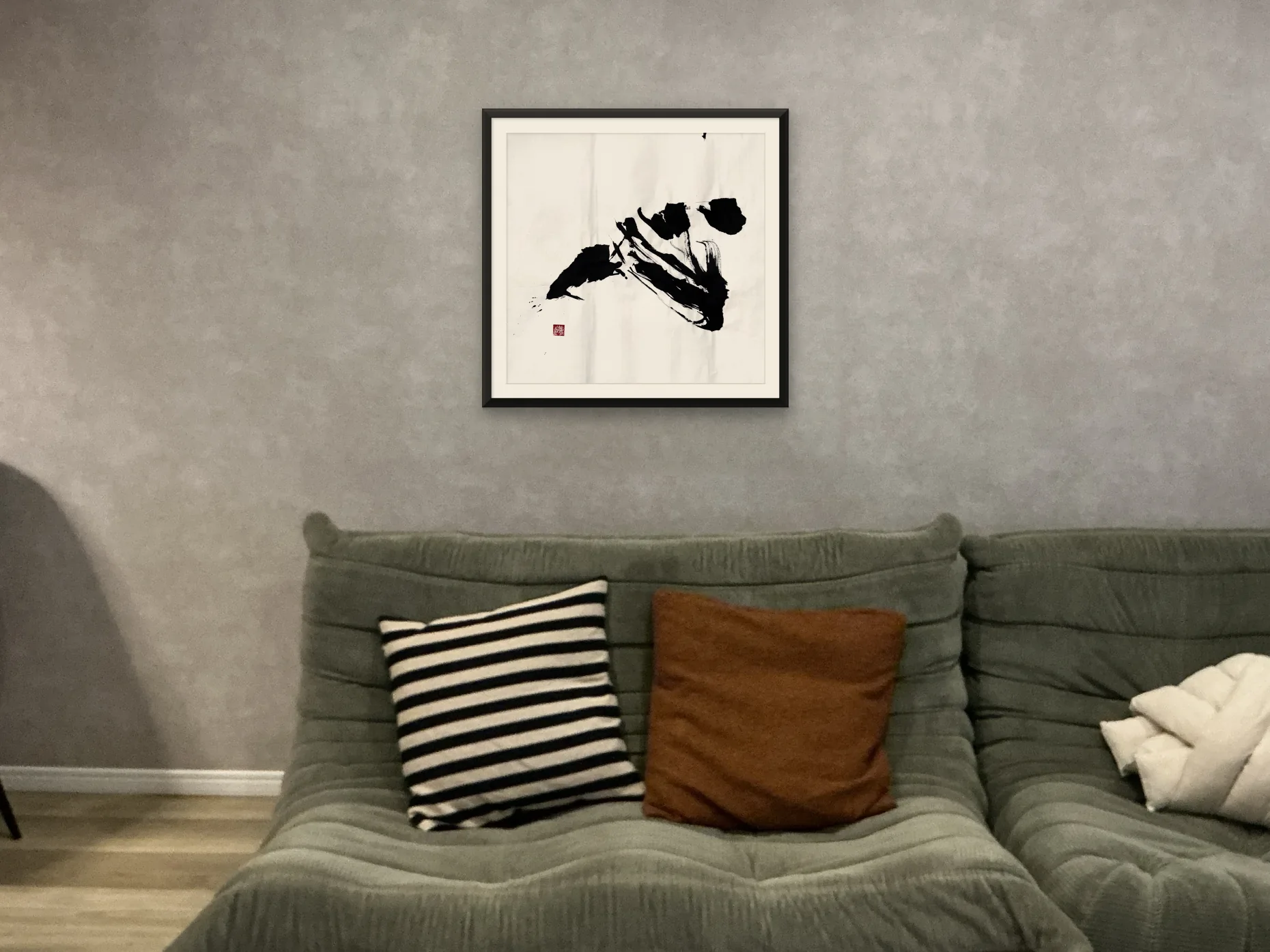 心 — Heart, framed in matte black with a warm white mount and hung on a grey wall. A simulated placement.